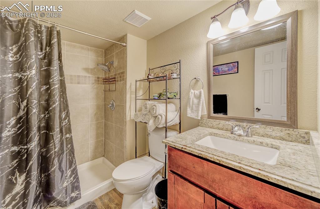 Image 20 of 25: Bathroom featuring vanity, a textured ceiling, hardwood / wood-style floori