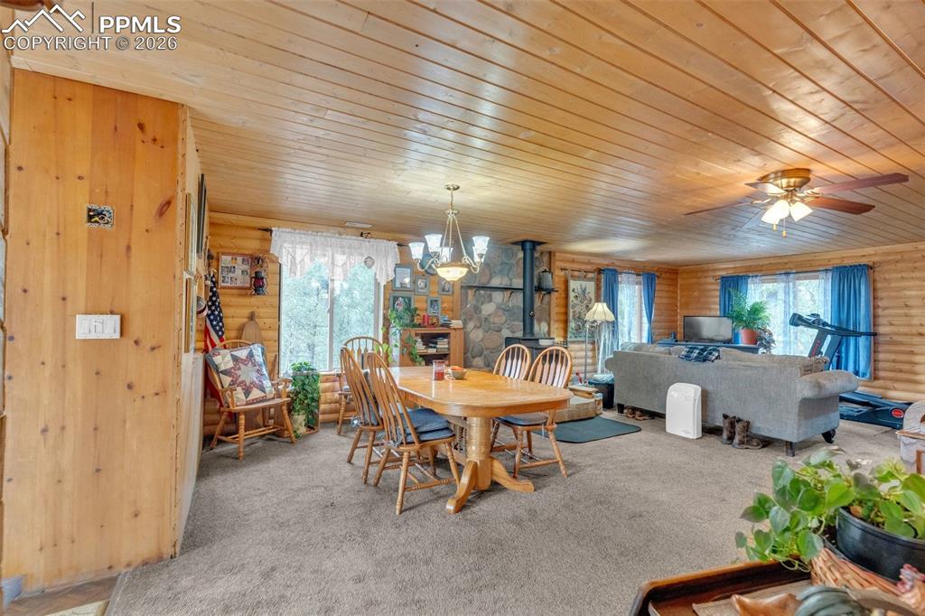 Image 10 of 41: Spacious room featuring log cabin walls, wood-paneled ceilings, and a centr