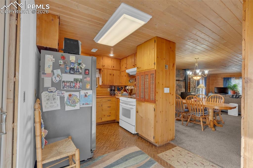 Image 13 of 41: Wood-paneled kitchen featuring abundant cabinetry, a white electric range,