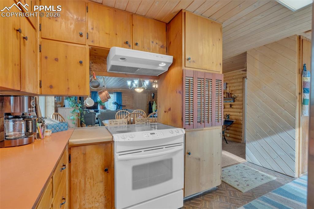 Image 14 of 41: Kitchen area featuring wood cabinetry, a white electric range, and an overh