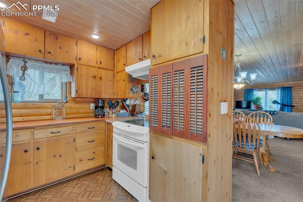 Image 15 of 41: Kitchen featuring wood cabinetry, wood-paneled walls, and a wood-slat ceili
