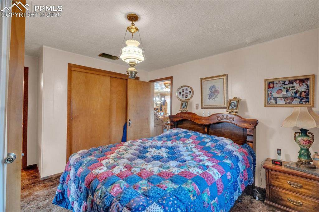 Image 18 of 41: Bedroom featuring a carved wood headboard, wood-finish sliding closet doors