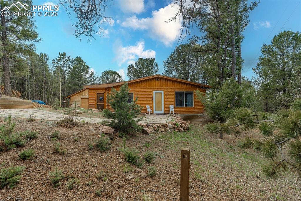 Image 2 of 41: Wood-sided residence surrounded by mature evergreen trees