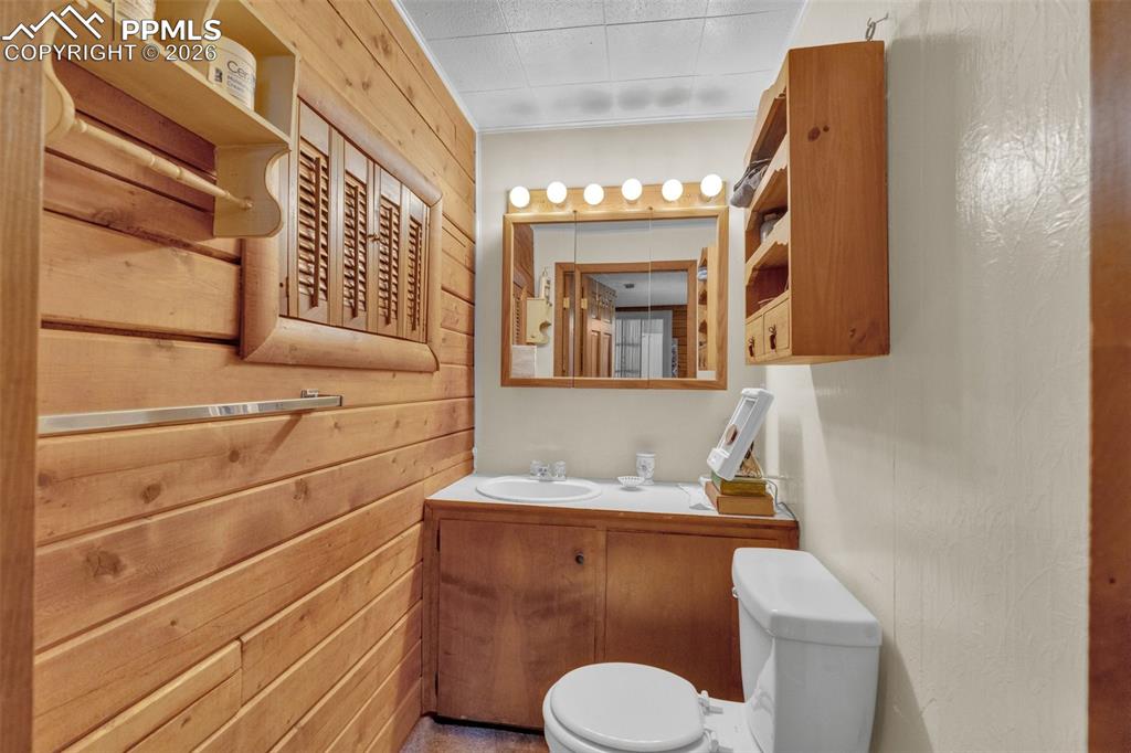 Image 20 of 41: Bathroom featuring wood-paneled walls, a single vanity with an integrated s