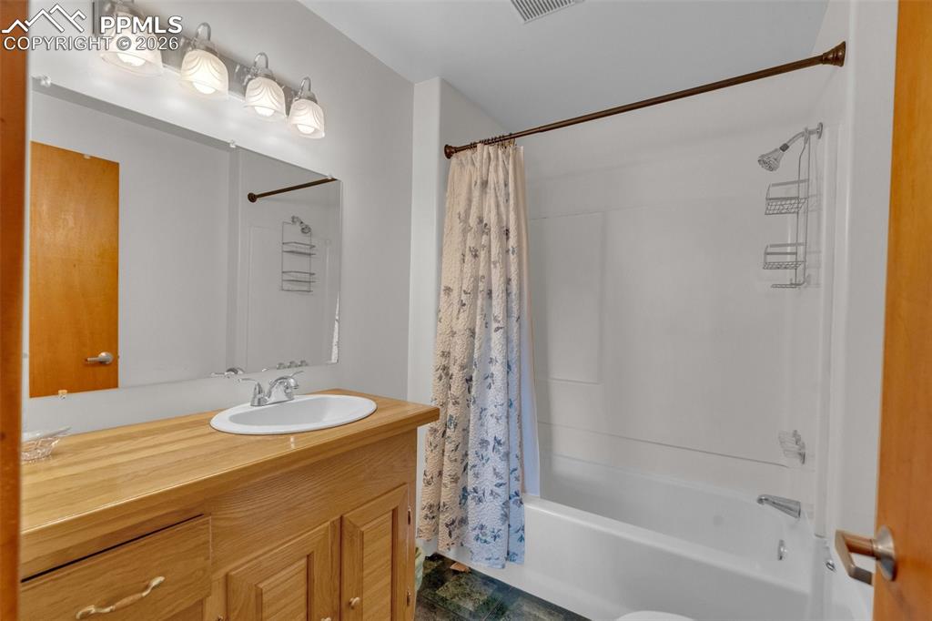 Image 21 of 41: Bathroom featuring a wood-finish vanity with an integrated sink, a large wa