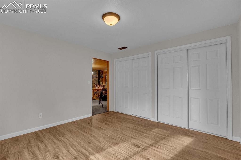 Image 23 of 41: Interior room featuring wood-finish flooring, two sets of white sliding clo