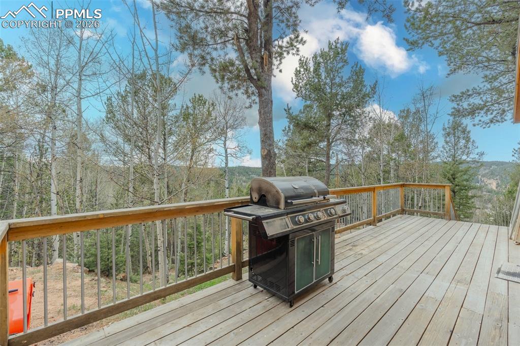 Image 26 of 41: Expansive outdoor deck with a natural wood finish, surrounded by mature tre