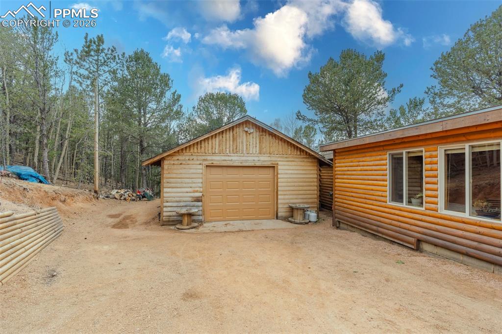 Image 3 of 41: Natural wood siding on two structures, featuring a single-car garage with a