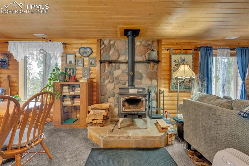 Image 6 of 41: Central wood-burning stove with a stone surround and hearth