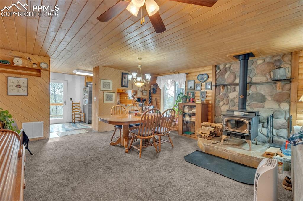 Image 9 of 41: Living area featuring a stone wood-burning stove, wood plank ceilings, wood