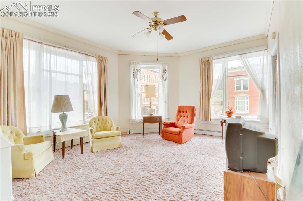 Image 18 of 36: Sitting room with ceiling fan, carpet floors, and ornamental molding