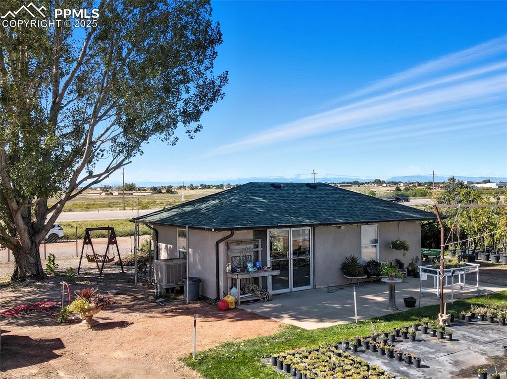 Image 3 of 12: Back of house featuring a shingled roof, stucco siding, and a patio
