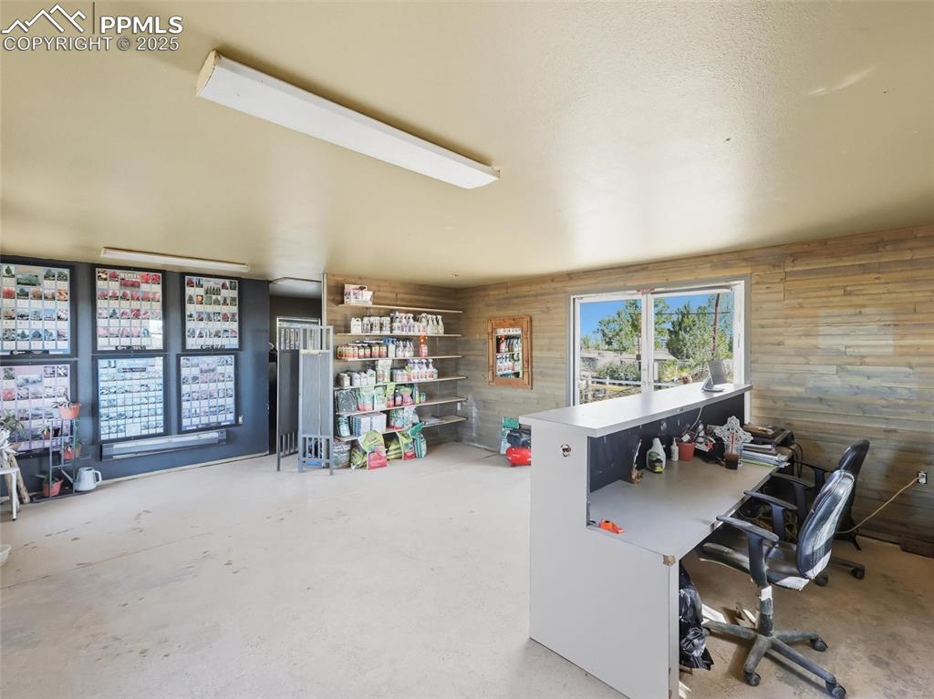 Image 6 of 12: Home office with wood walls and unfinished concrete flooring