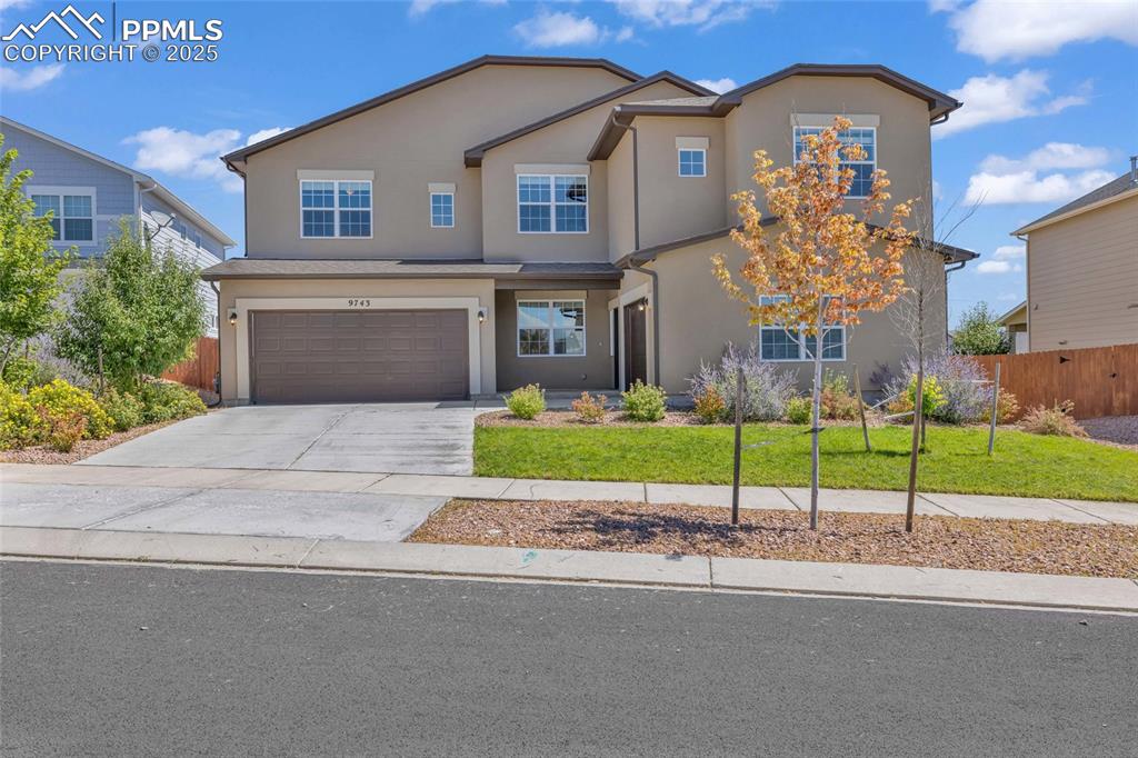 Caption: Traditional-style home with driveway, a garage, and stucco siding