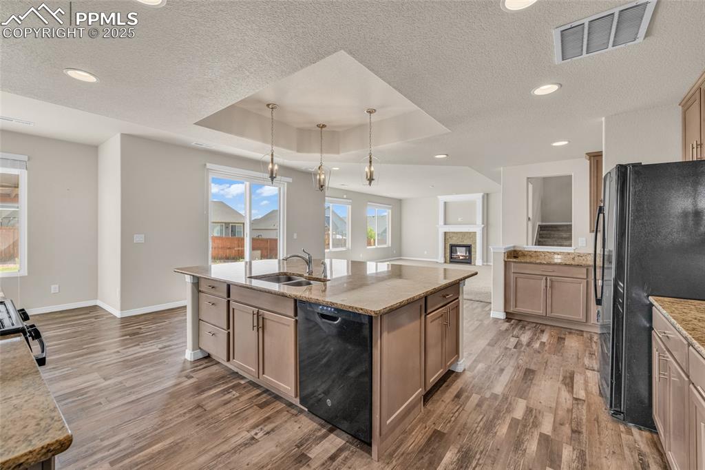 Image 14 of 44: Kitchen with a raised ceiling, black appliances, light wood-style floors, l