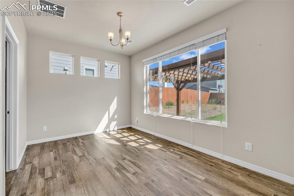 Image 15 of 44: Unfurnished dining area with wood finished floors and a chandelier