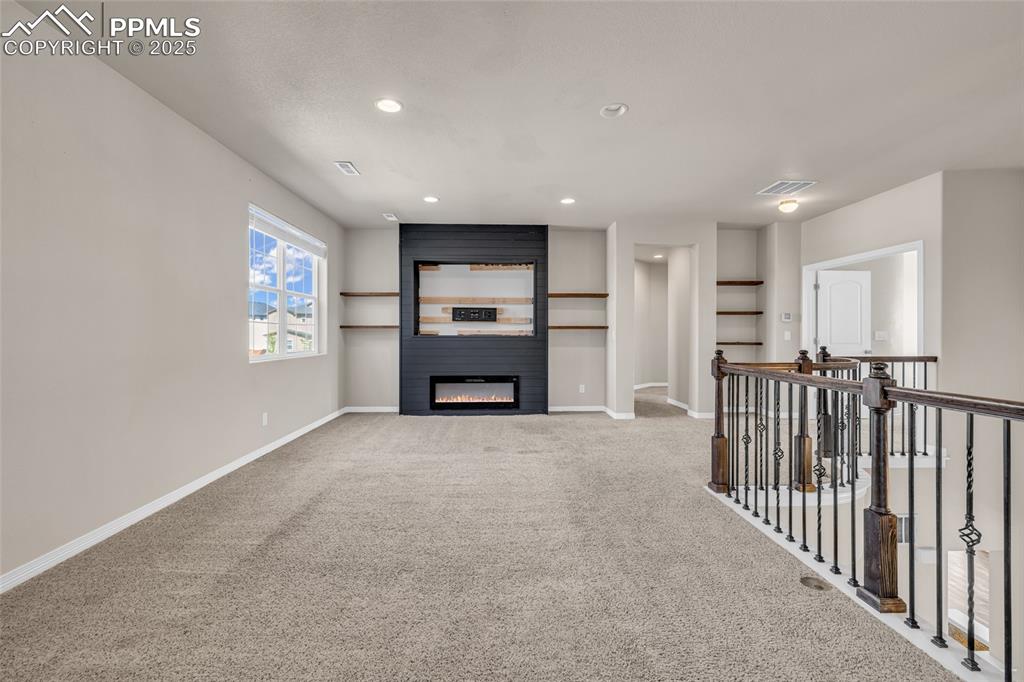 Image 18 of 44: Unfurnished living room featuring carpet floors, a fireplace, and recessed 