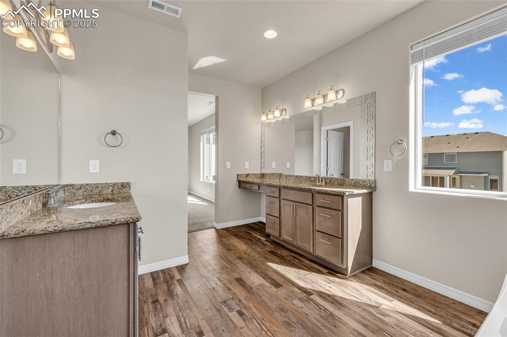 Image 24 of 44: Bathroom with two vanities, dark wood-style floors, and recessed lighting