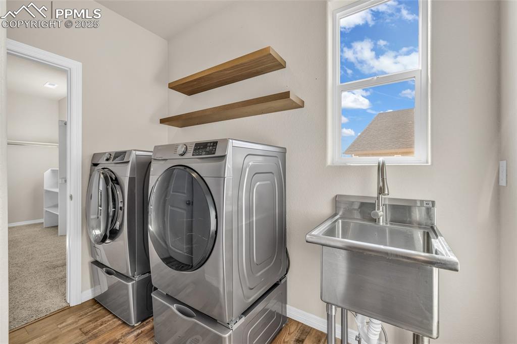 Image 26 of 44: Laundry area with wood finished floors and washing machine and clothes drye