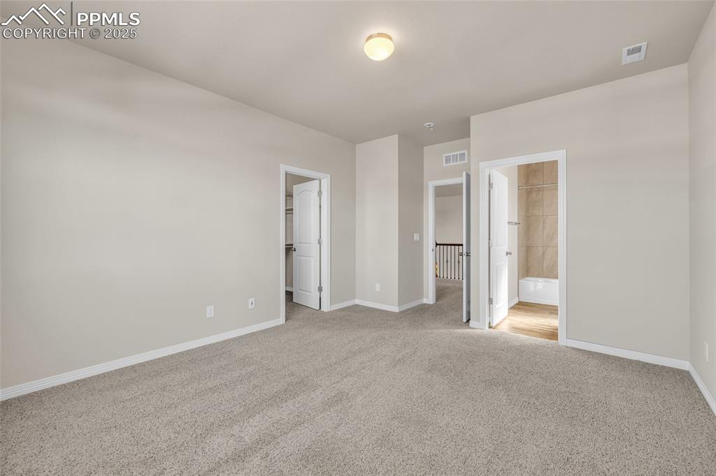 Image 28 of 44: Unfurnished bedroom with a walk in closet, light colored carpet, and connec