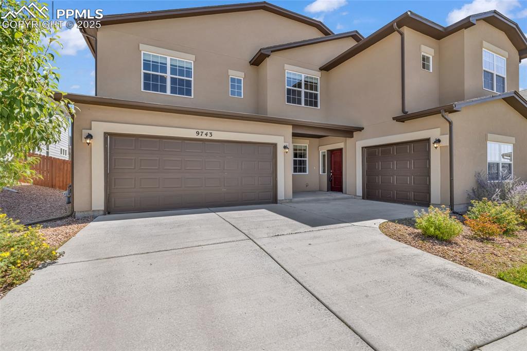 Image 4 of 44: Traditional-style house with a garage, stucco siding, and driveway