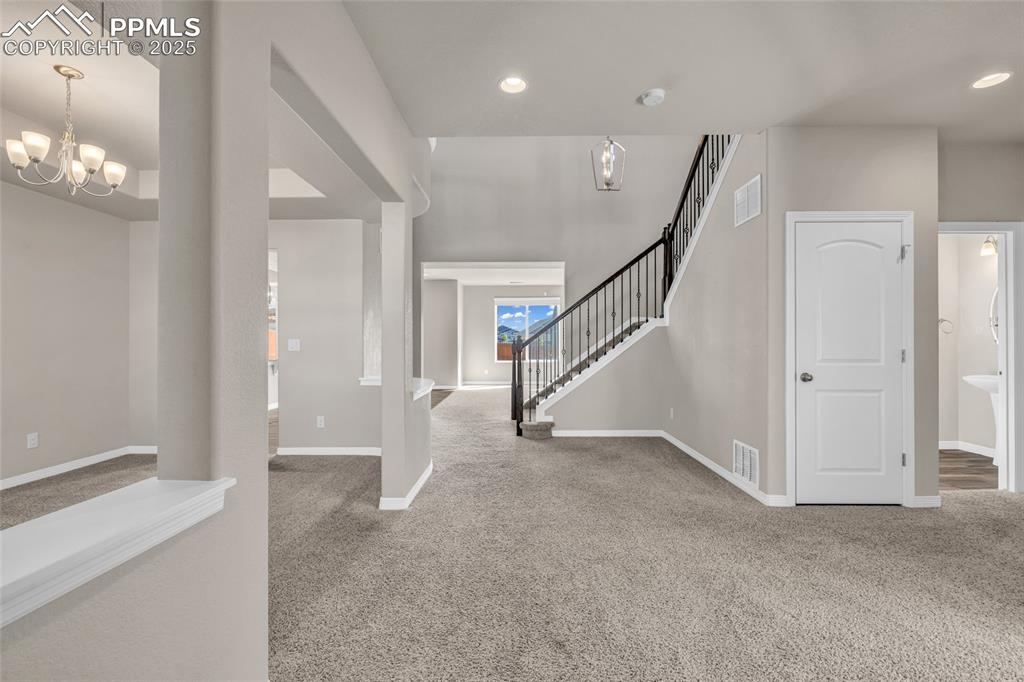 Image 6 of 44: Entryway with light colored carpet, stairs, a chandelier, and recessed ligh