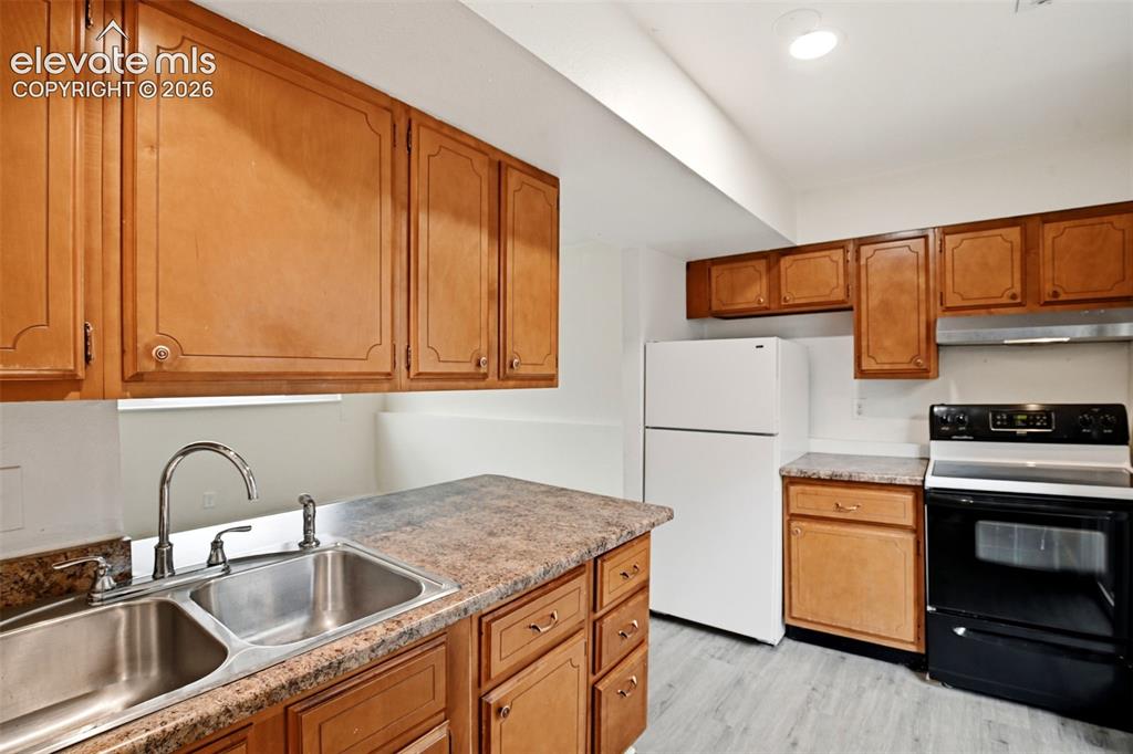 Image 15 of 31: Kitchen featuring wood cabinetry, laminate countertops, a double basin stai