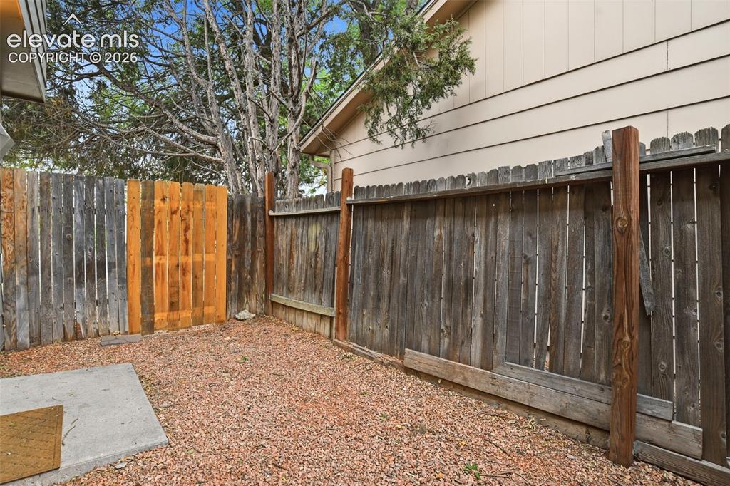 Image 20 of 31: Enclosed backyard space featuring a wood fence, gravel ground covering, and