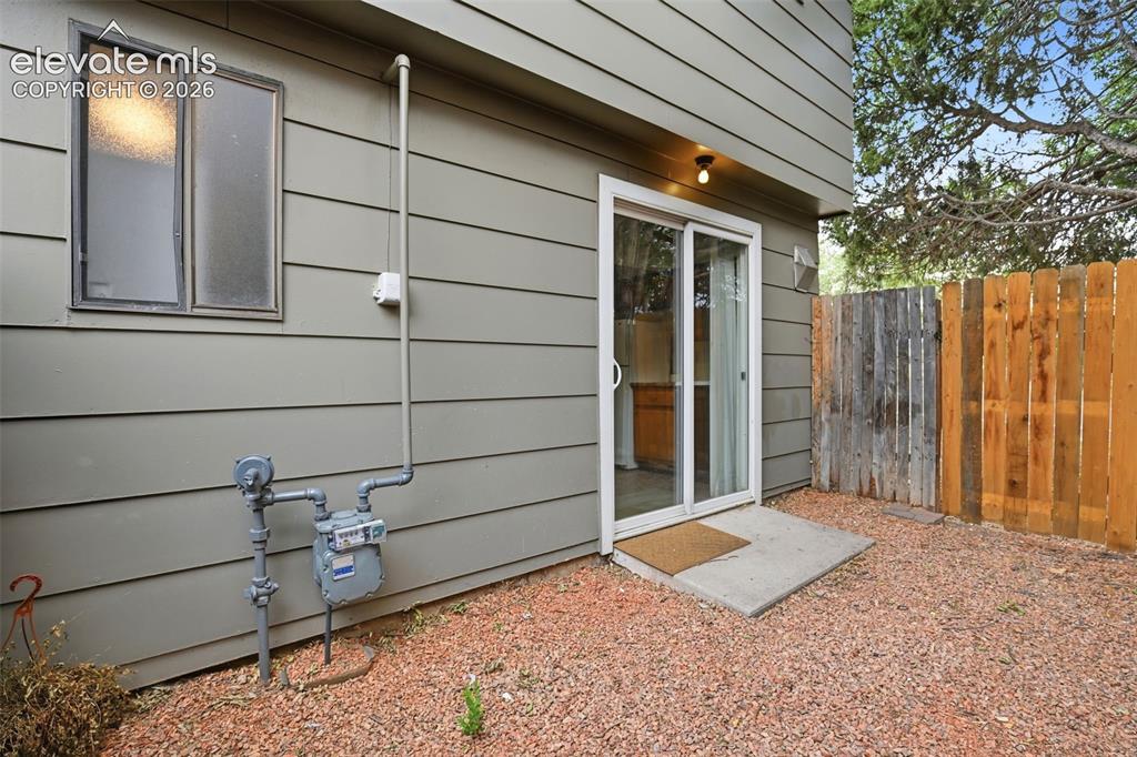 Image 21 of 31: Sliding glass door entry, concrete landing, horizontal siding, gravel groun
