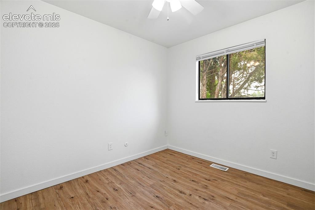 Image 24 of 31: Wood-finish flooring, white walls, and a window with horizontal blinds