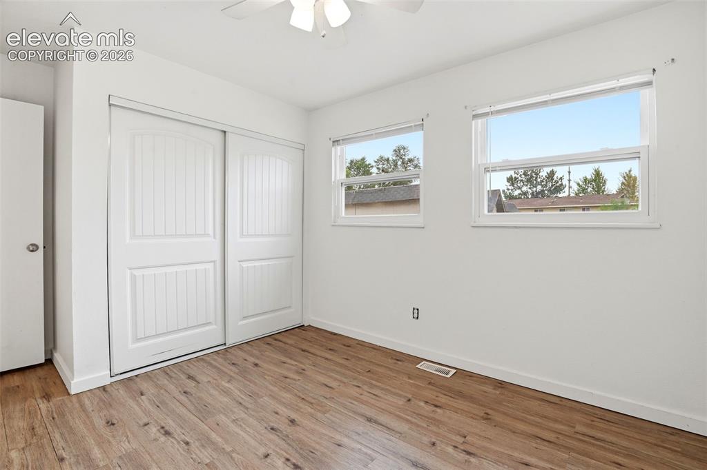 Image 26 of 31: Wood-finish flooring, two large windows, white walls, built-in bi-fold clos