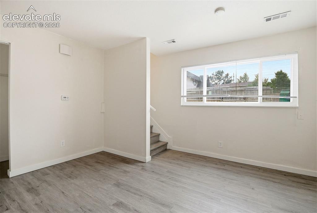 Image 5 of 31: Living Room is Left Down the Stairs and Adjacent to the Kitchen