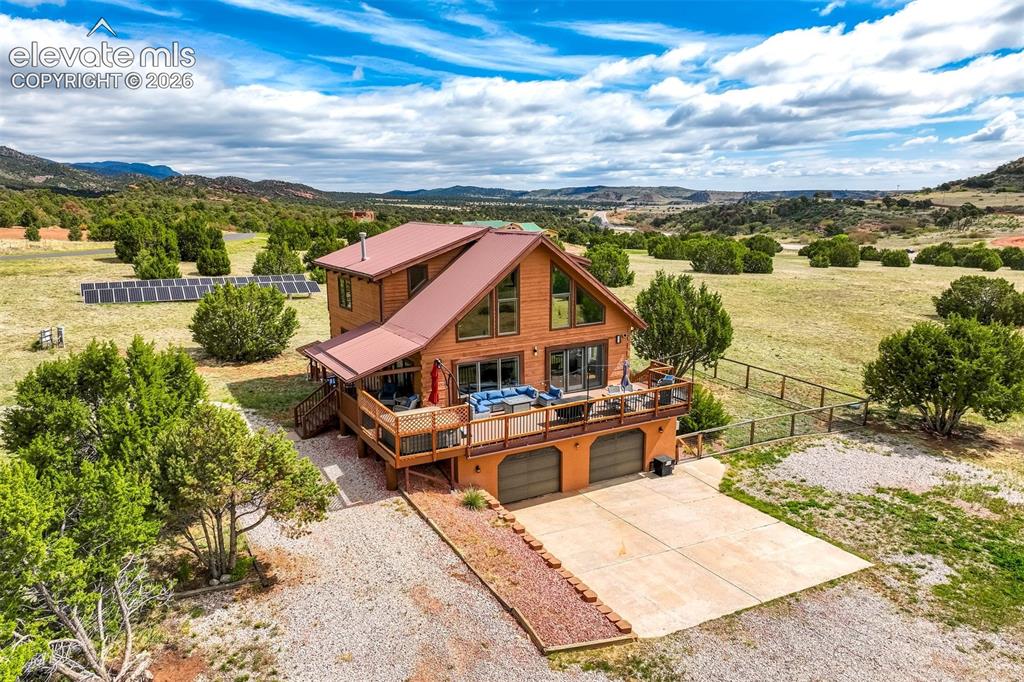 Image 1 of 50: Wood-sided residence with a reddish-brown metal roof and a spacious elevate