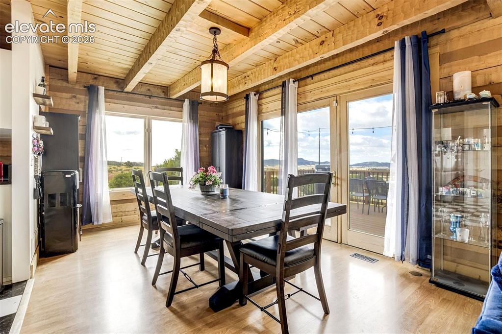 Image 12 of 50: Dining area featuring extensive wood-paneled walls and exposed beam ceiling
