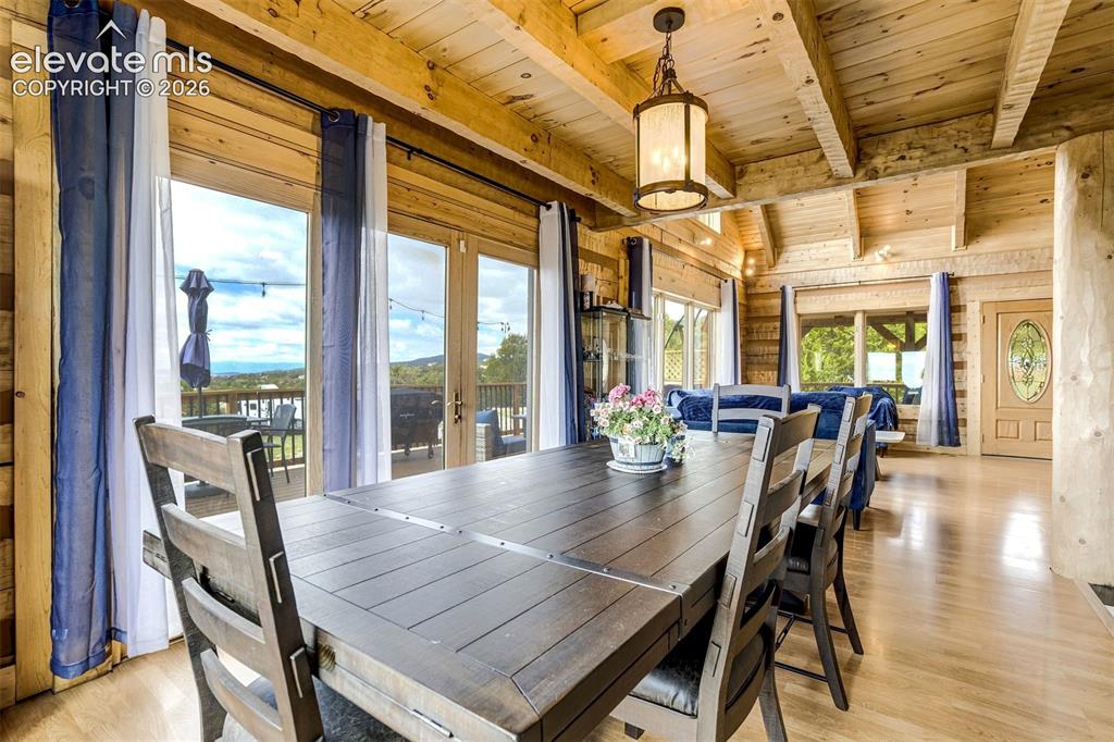 Image 13 of 50: Spacious dining area featuring exposed wood beams and wood-finish flooring