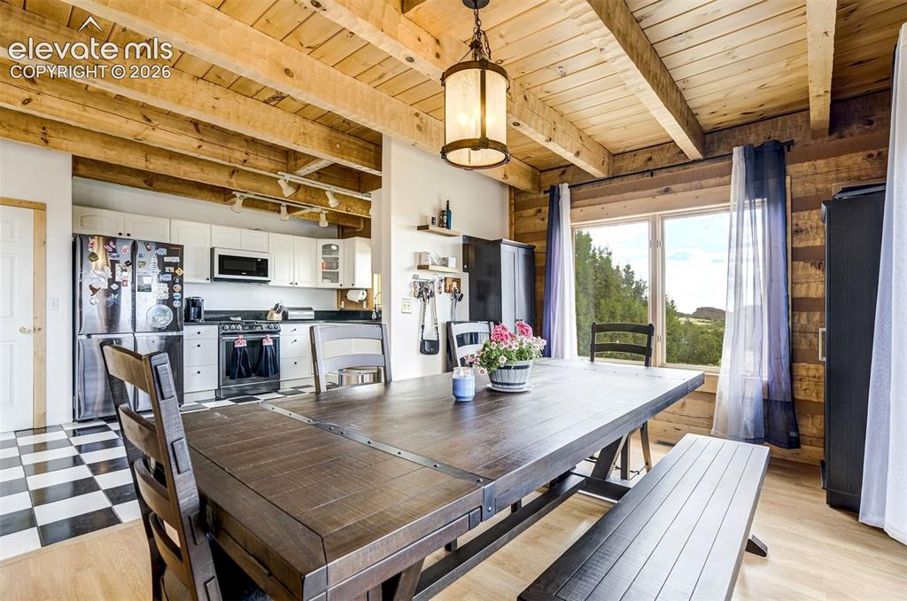 Image 14 of 50: Exposed wood beam ceiling and wood plank wall paneling define this dining a