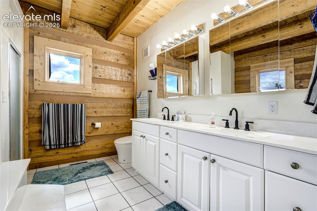 Image 21 of 50: Bathroom featuring wood-paneled walls and a wooden beamed ceiling
