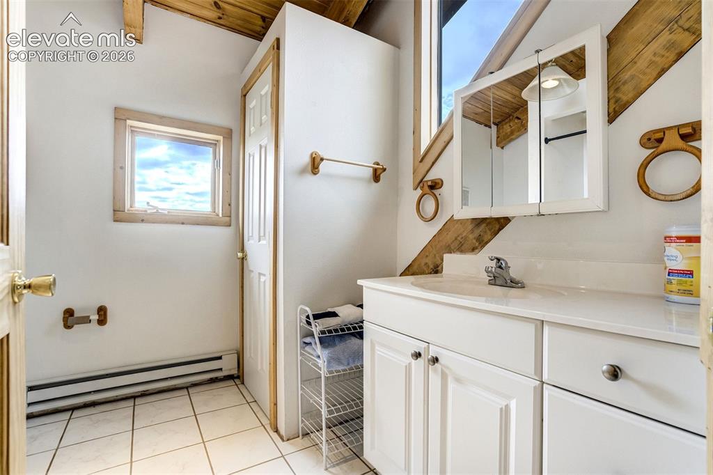 Image 28 of 50: Bathroom featuring a single vanity with white cabinetry, an integrated sink