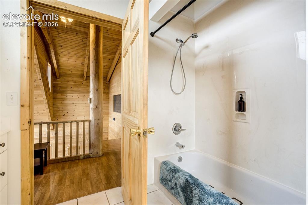Image 29 of 50: Bathroom featuring a bathtub with an integrated shower, chrome fixtures, an