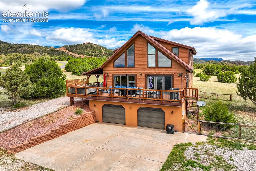Image 3 of 50: Cedar-sided home featuring a prominent upper-level deck, pitched roofline,
