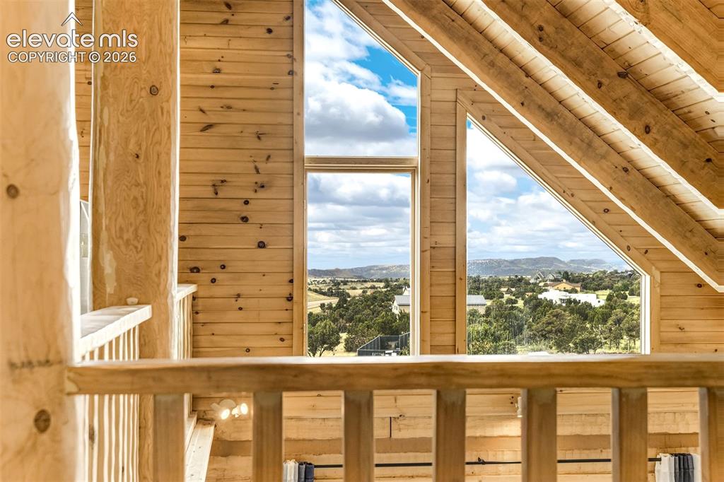 Image 32 of 50: Vaulted wood-finish ceilings and exposed beams complement the wood-paneled