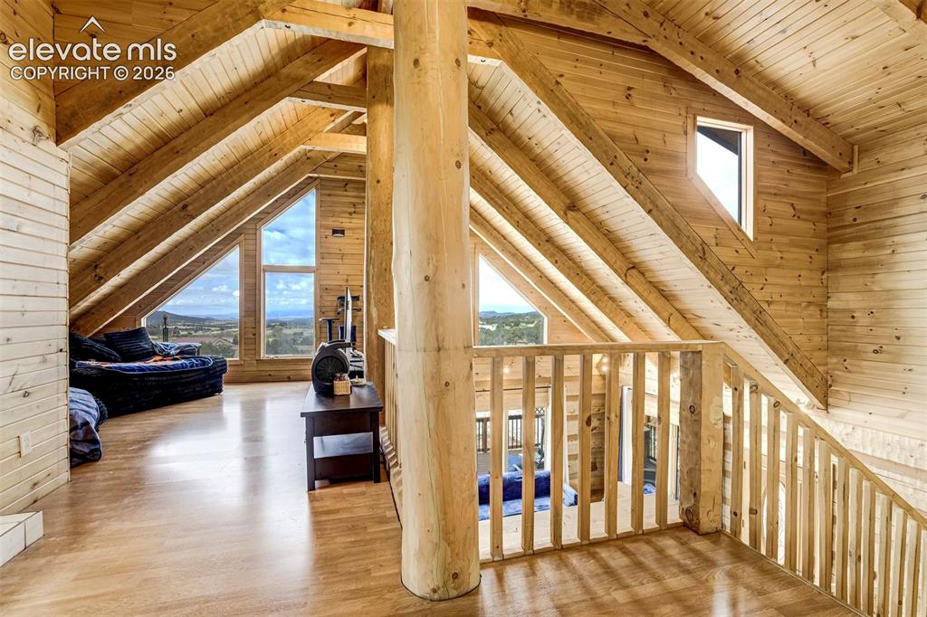 Image 33 of 50: Vaulted ceiling with exposed wood beams, natural wood-finish flooring, and