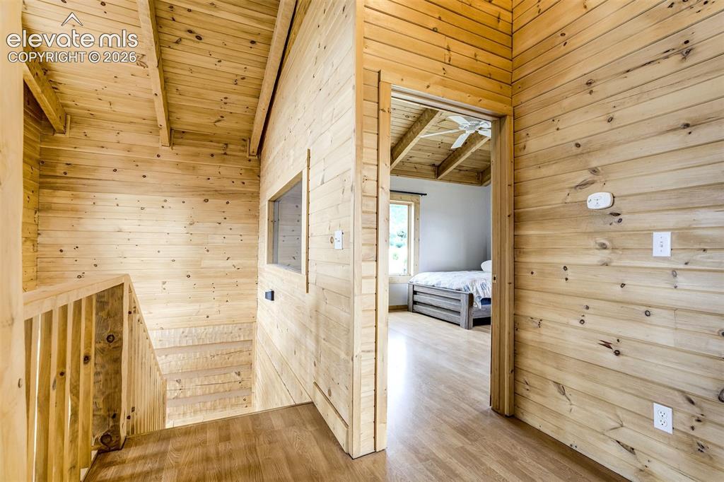 Image 36 of 50: Wood-paneled hallway featuring a wood-finish flooring, staircase with wood