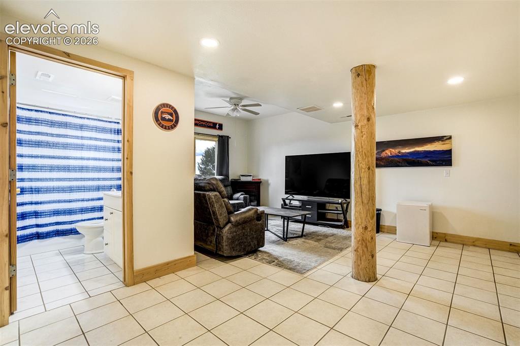 Image 38 of 50: Open concept living area with tiled flooring, featuring a natural wood supp