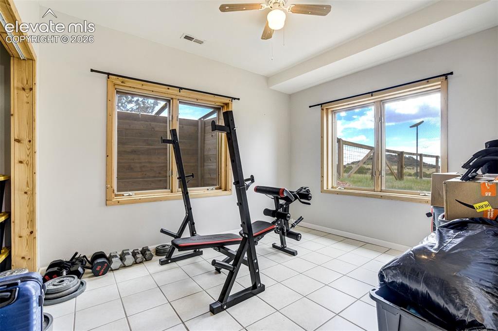 Image 41 of 50: Versatile room featuring two windows with natural wood trim, white tile flo