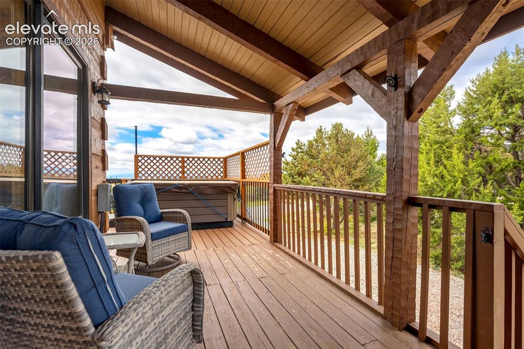 Image 47 of 50: Covered deck featuring a built-in hot tub, durable wood-finish flooring, an