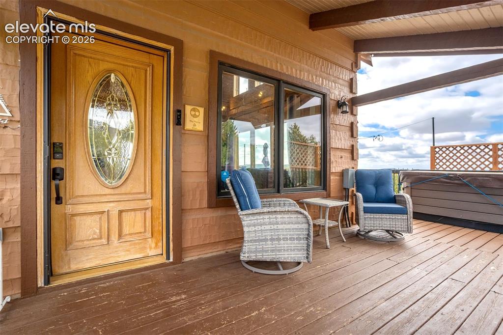 Image 5 of 50: Wood-finish decking with a covered porch featuring a decorative glass panel