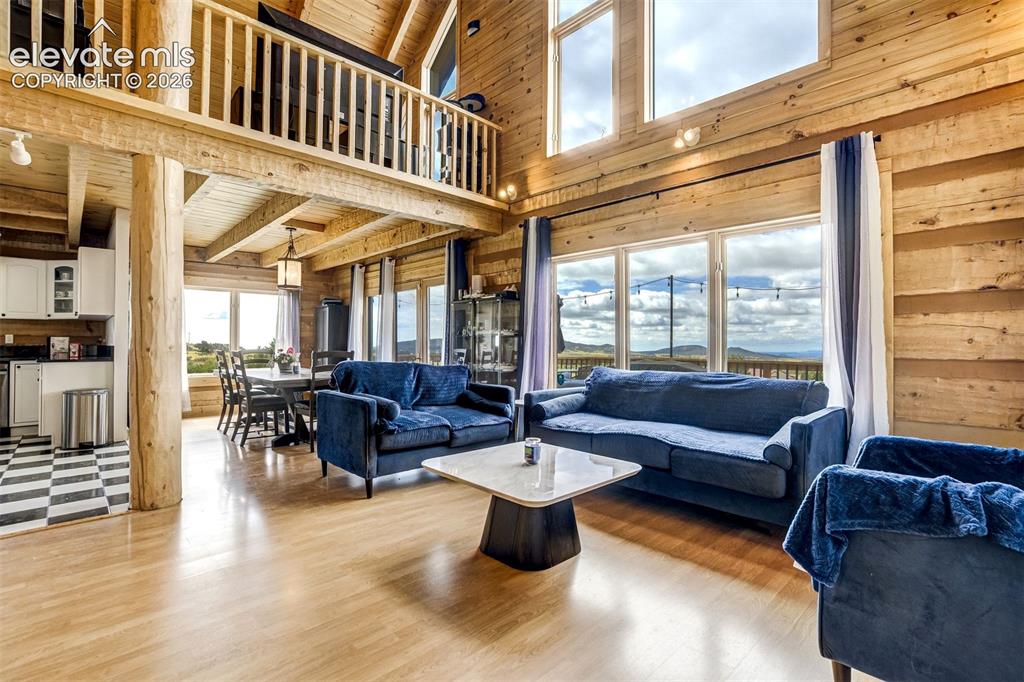 Image 6 of 50: Expansive living area featuring soaring ceilings with exposed wood beams, a