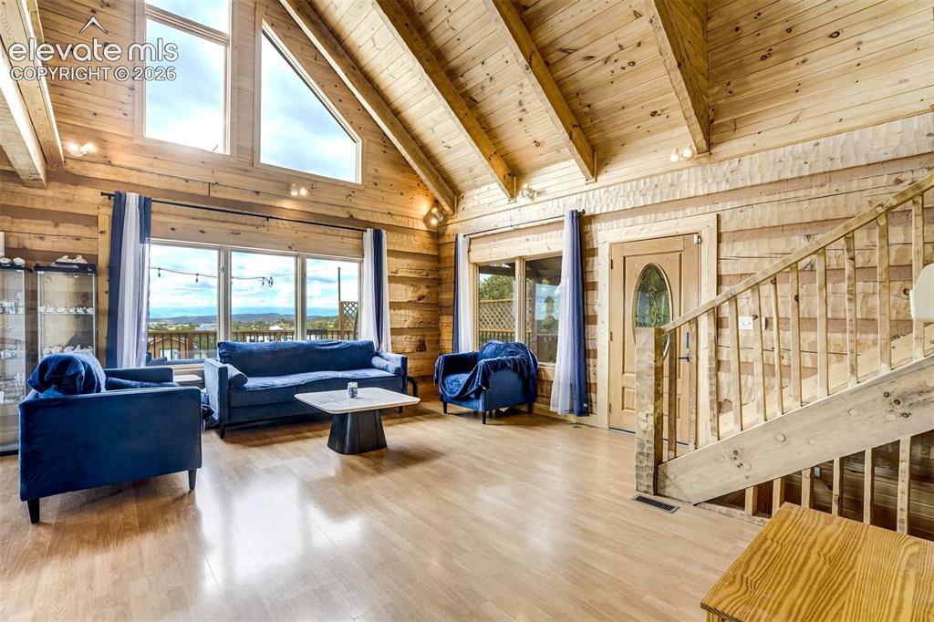 Image 7 of 50: Spacious living area featuring expansive windows, wood-finish flooring, exp