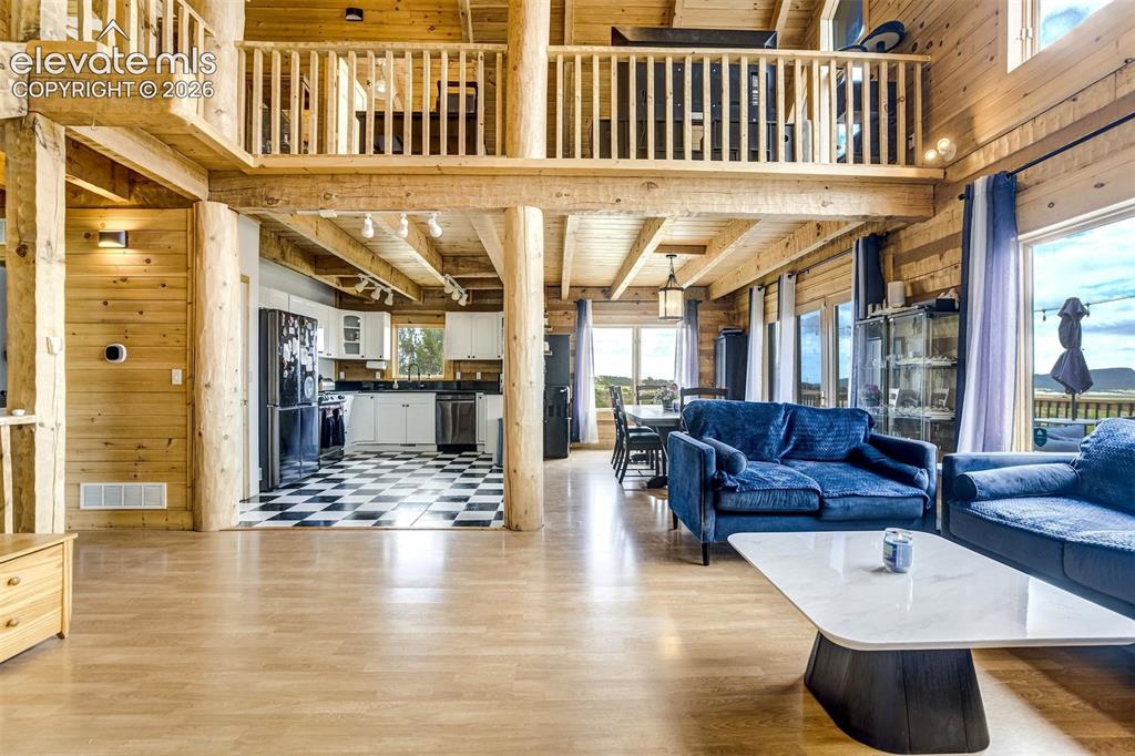Image 8 of 50: Expansive open-concept living space featuring wood-finish flooring, exposed